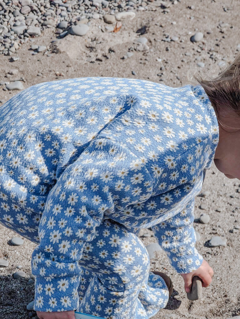 sweater on child playing with rocks in sand 