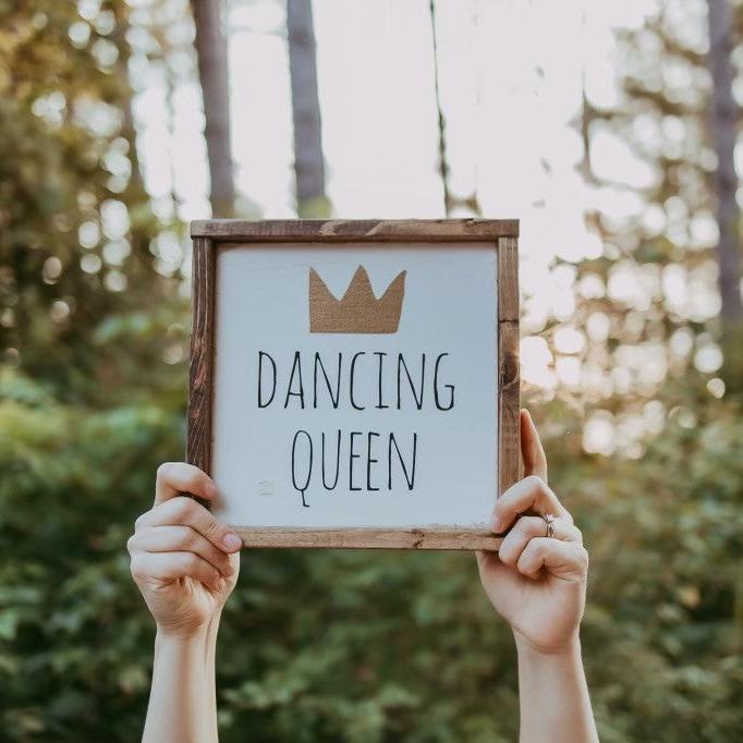 dancing queen sign in hands with trees in background 