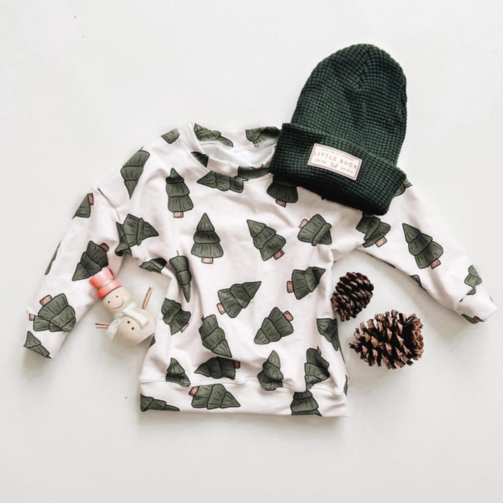 white crewneck with trees and green hat flat lay