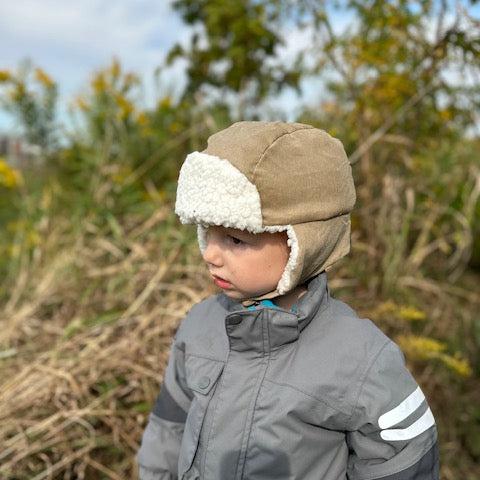 beige hat on boy n grey coat in field