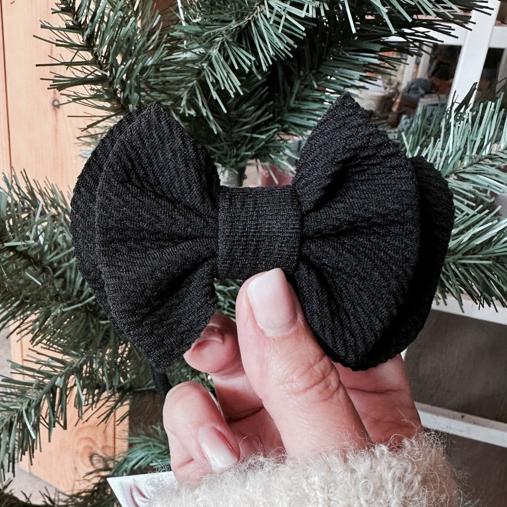 Black bow in front of pine tree
