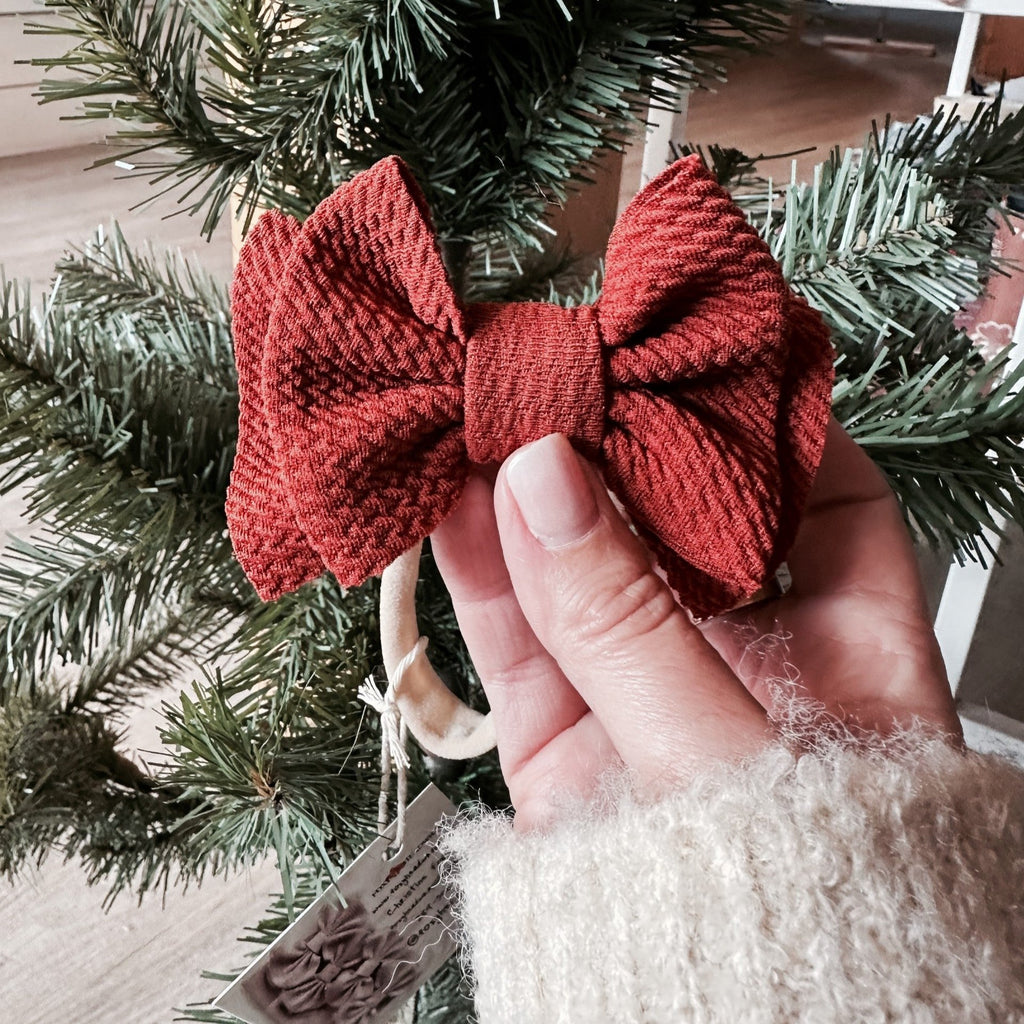 cinnamon mini bow in front of pine tree