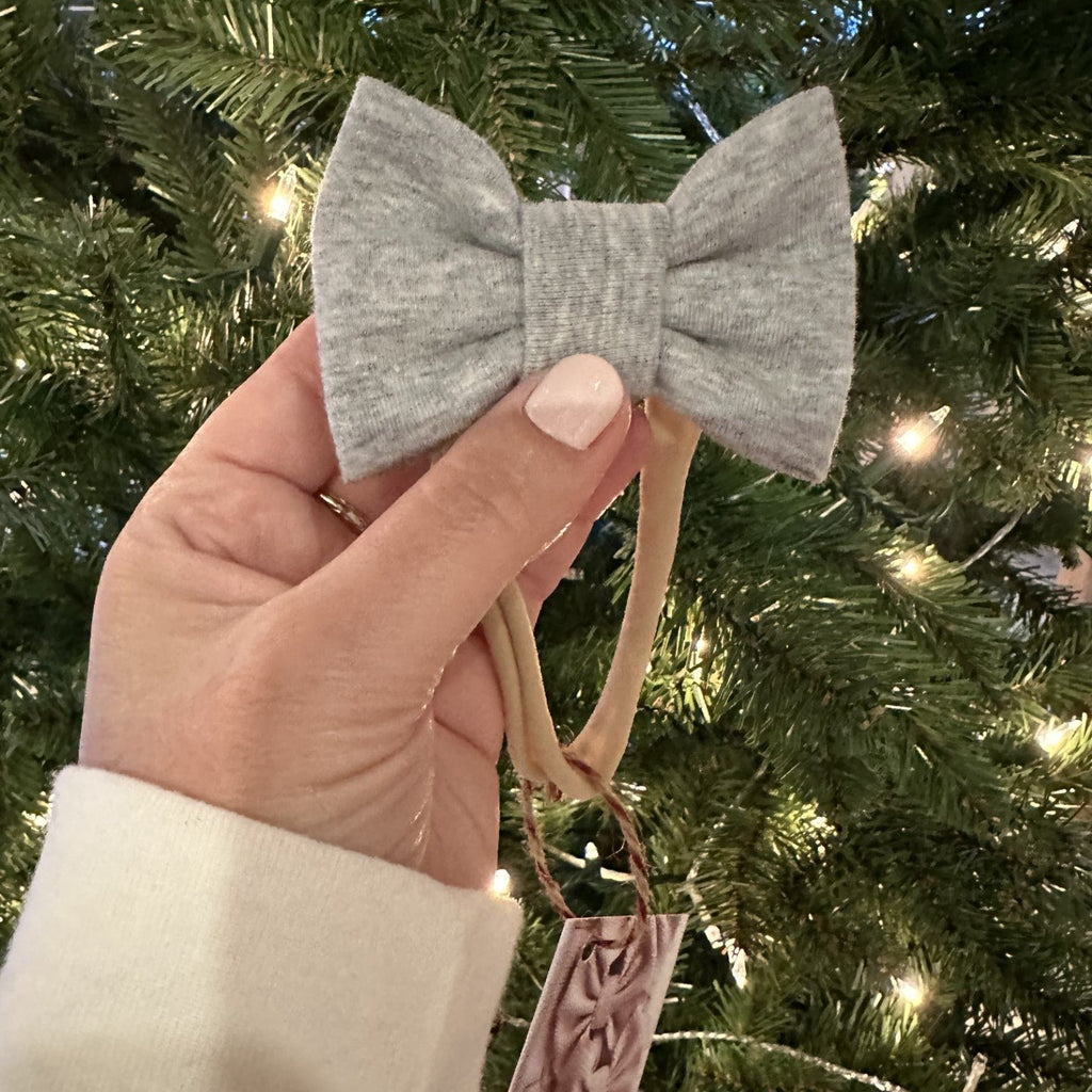 grey mini bow in front of tree