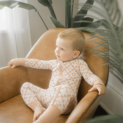 Baby sitting in brown chair wth plants