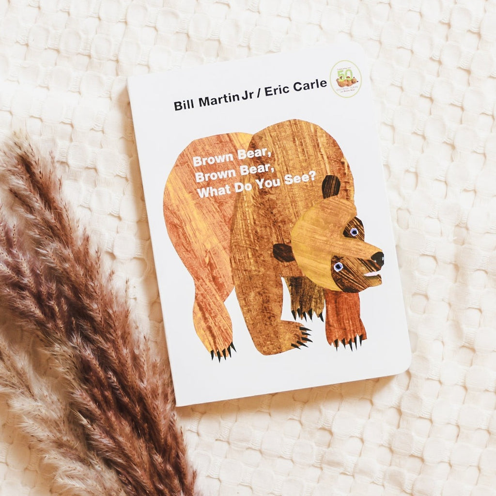 Cream waffle throw background with the book Brown Bear, Brown Bear, What Do You See? by Bill Martin Jr. in the middle and pampas grass to the side. Cover is white with a large drawing of a bear.