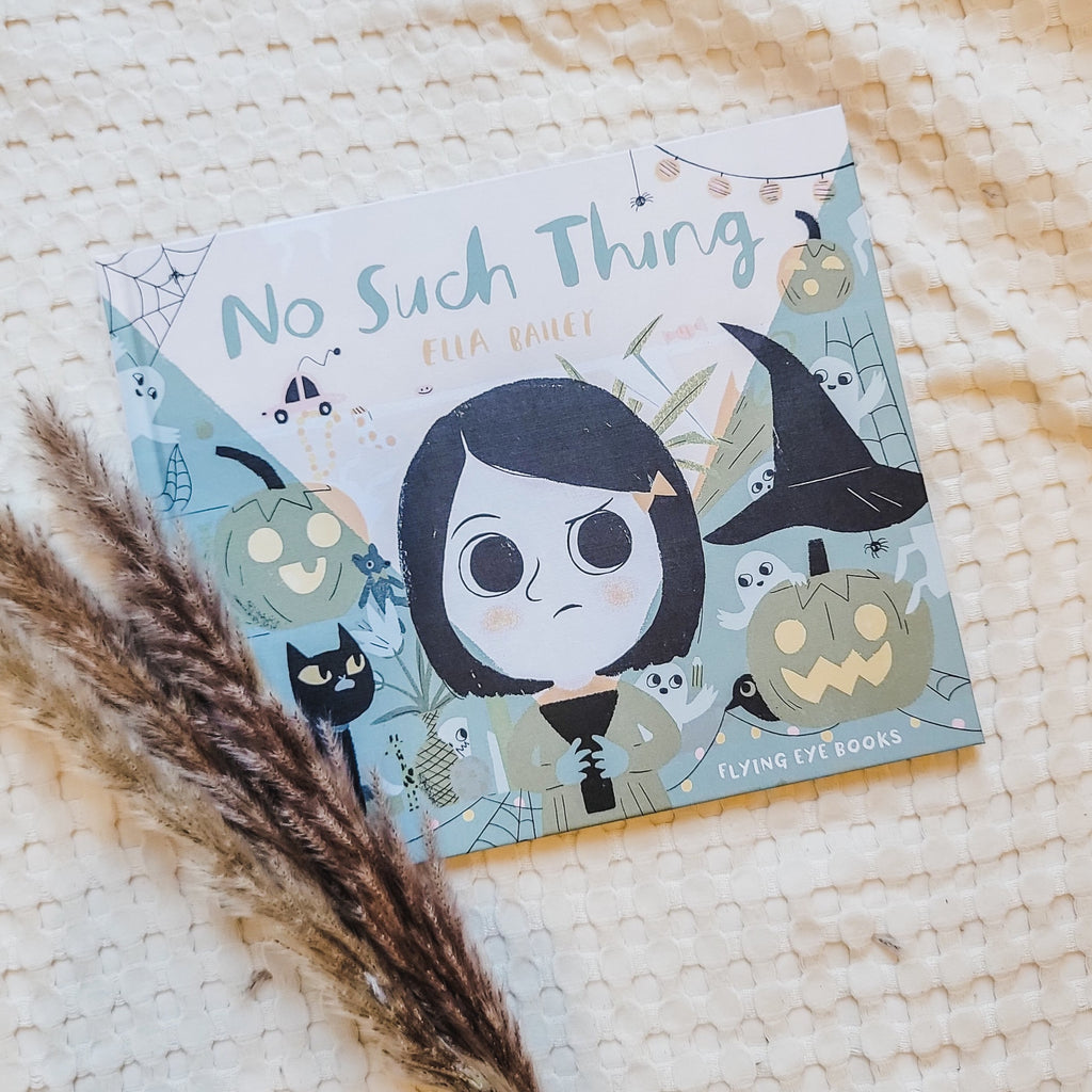Cream waffle blanket with pampas grass on the bottom left corner with the book No Such Thing by Ella Bailey. Cover shows a girl standing, shining a flashlight with pumpkins, cats, and ghosts all around.