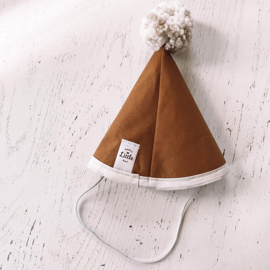 Washed white wood background with Mustard Fabric Party Hat with Beige Pompom by Fancy Little Day