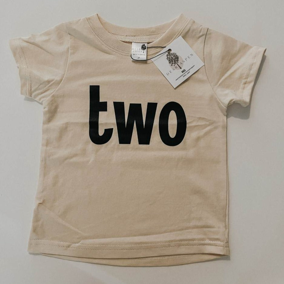 two birthday tee by Dear Aspen, laid on a flat white surface. 