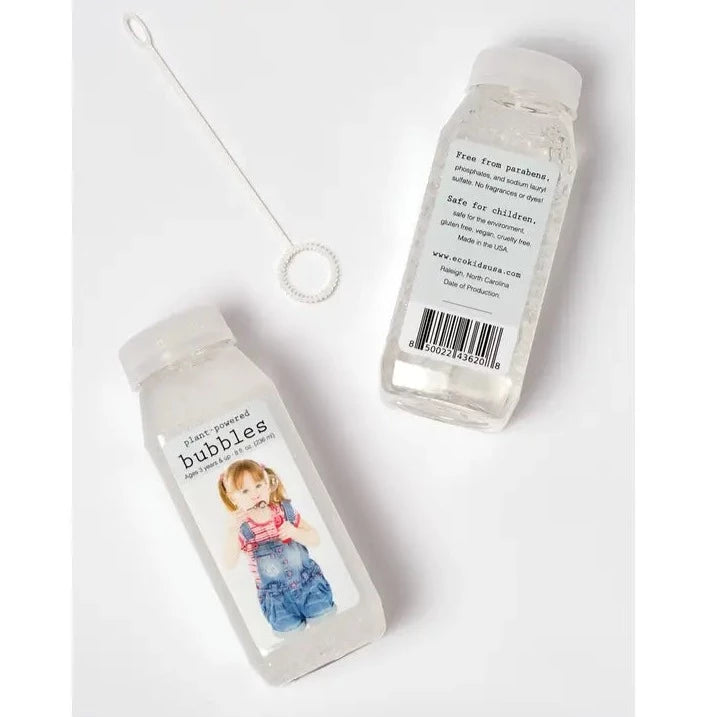 Bubbles by Eco-Kids, front of bottle and back of bottle with the blowing wand, laid on a flat white surface. 