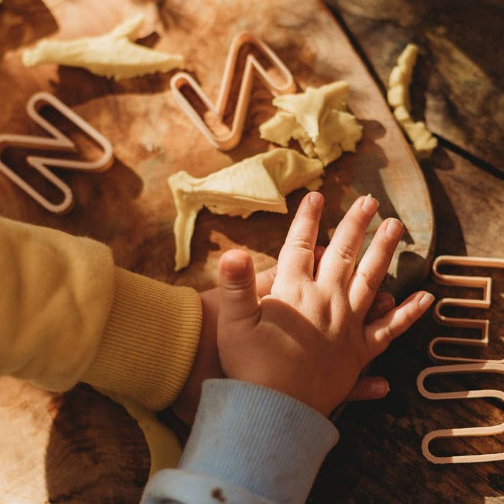 Alphabet Eco Cutter Set by Kinfolk Pantry with child's hand and play dough