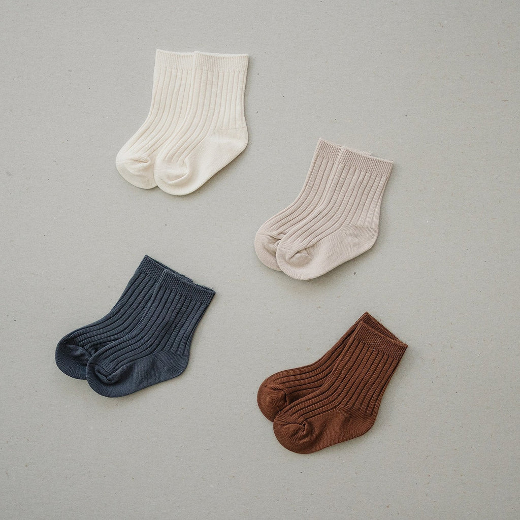 Mebie Baby socks laid on a flat surface. Vanilla, Oatmeal, Rust and Charcoal colours. 
