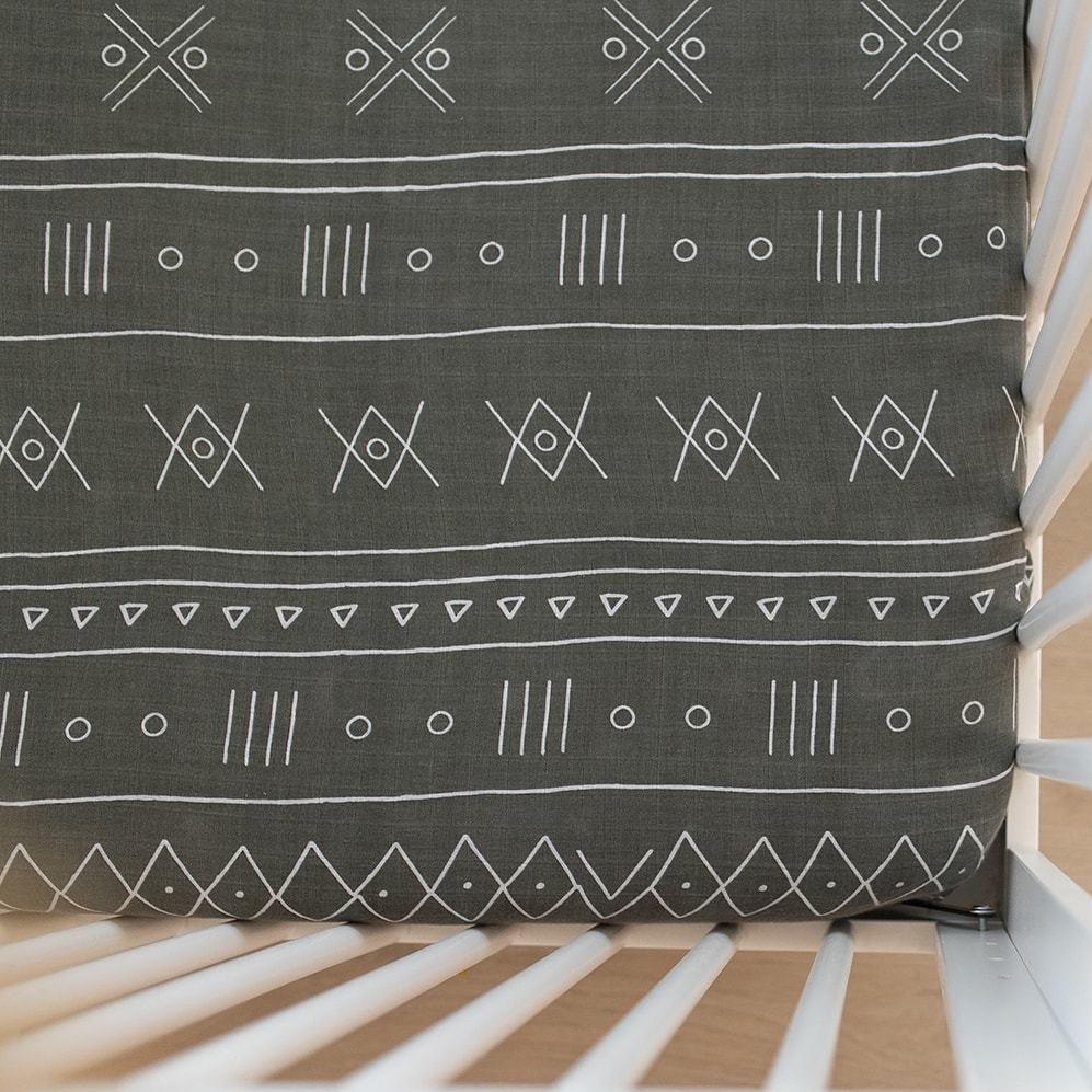 Overhead view of Alpine Crib Sheet by Mebie Baby on a mattress. Crib Sheet is green with an aztec print, and fits snug to the mattress.