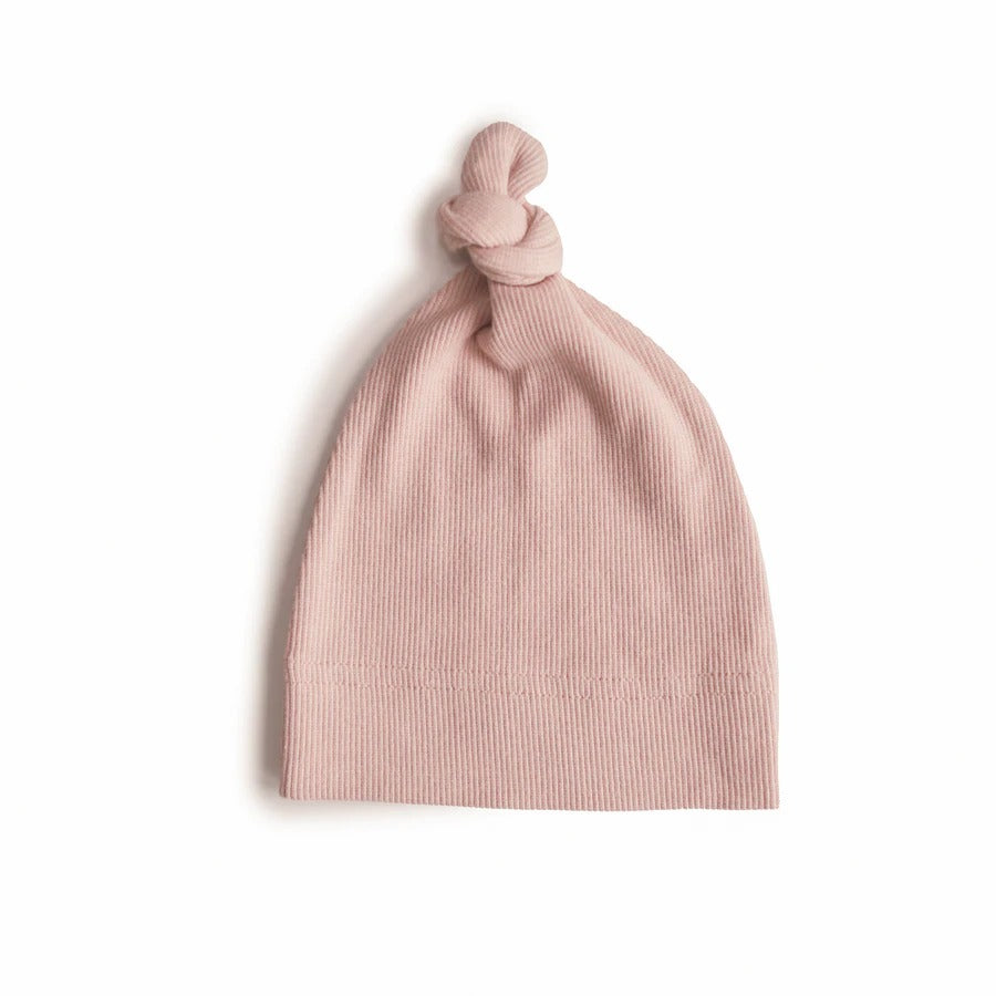 White background with a Ribbed Baby Beanie in Blush by Mushie. The beanie is a ribbed blush colour with a knot on the top.