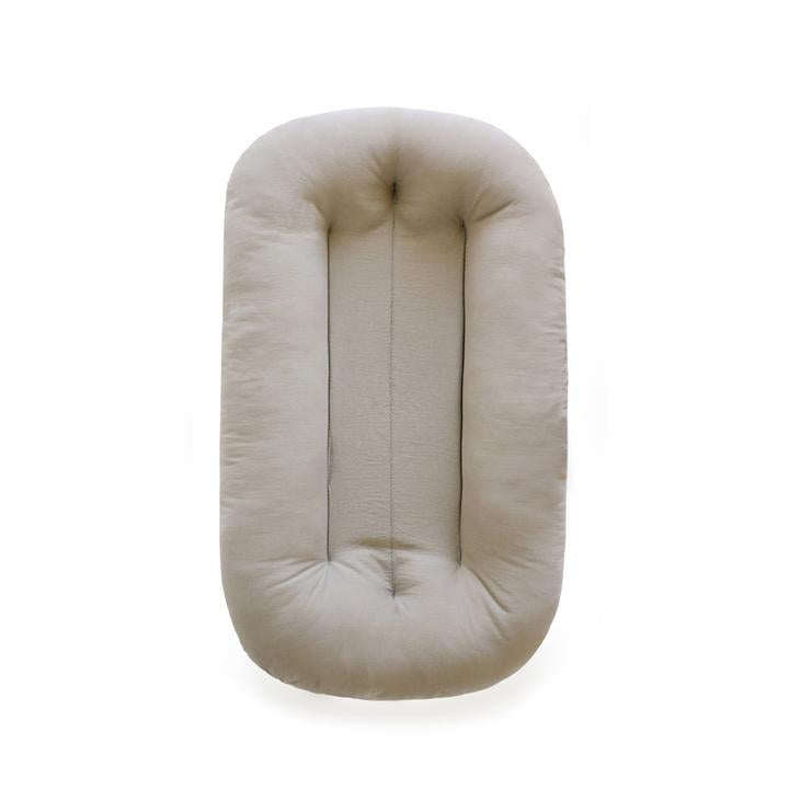 White background with the Snuggle Me Organic Infant Lounger in Birch by Snuggle Me. Lounger is an oatmeal colour.