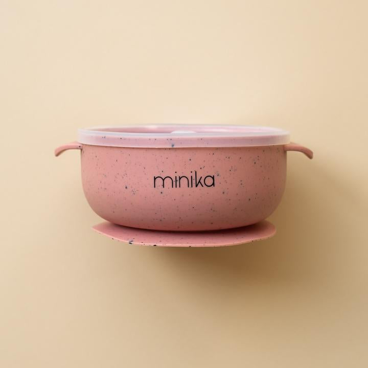 Beige background with a Silicone Bowl with Lid in Sorbet by Minika. Bowl is rose speckled, has a silicone base to stick to your table, and a clear lid.