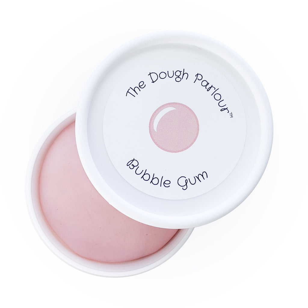 White background with Bubblegum Play Dough by Dough Parlour, open slightly to show. Play dough is a pale pink in a white container, lid has a sticker that says "Bubblegum".