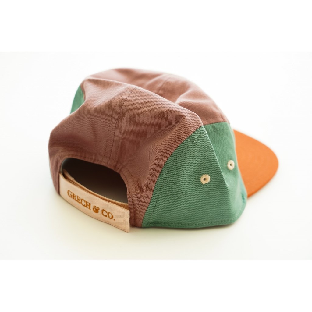 White background with backside of 5 Panel Hat in Burlwood + Shell by Grech & Co. This hat features 3 different colours, a mauve, turquoise and rust, with a cream velcro strap that says "Grech & Co." in rust.