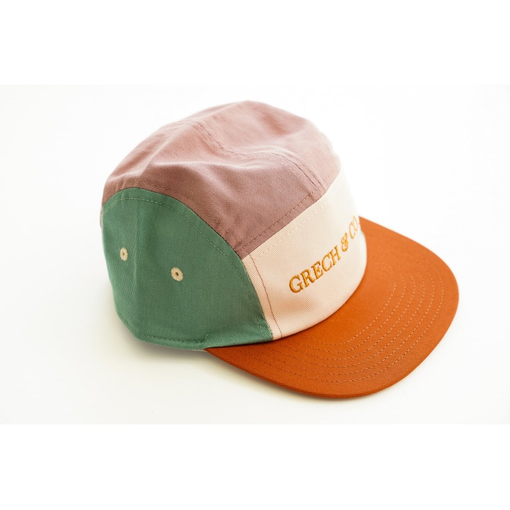 White background with 5 Panel hat in Burlwood + Shell by Grech & Co. This hat features 3 different colours, a mauve, turquoise and rust, with a cream front panel with "Grech & Co." across in rust.
