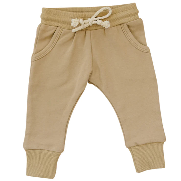 White background with Cafe French Terry Joggers by Mebie Baby. Joggers are a beige colour with pockets, tight at the ankle, and a white drawstring.