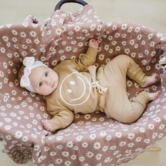 Overhead view of a baby girl laying in a bassinet, wearing the Cafe French Terry Joggers by Mebie Baby.