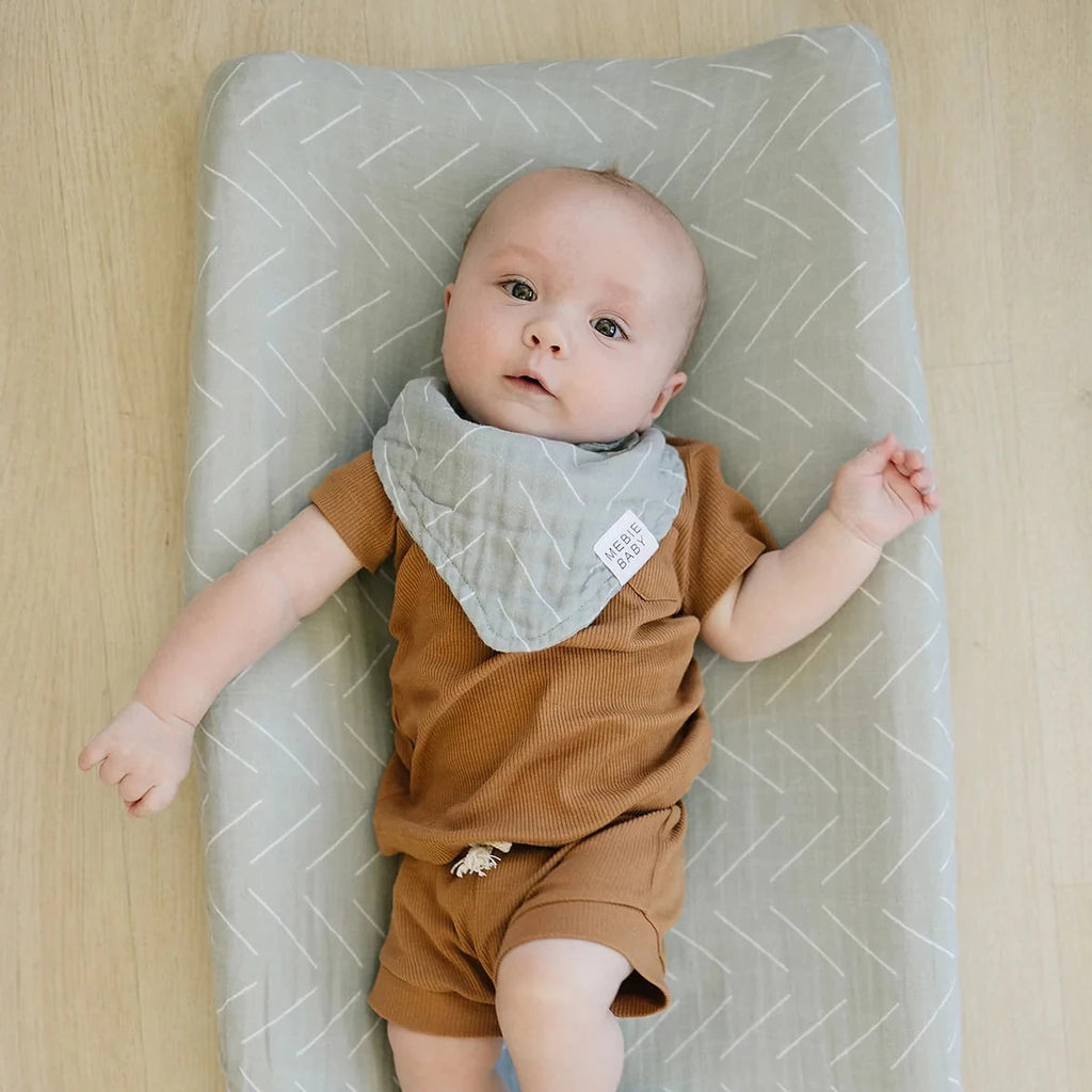 Overhead view of baby boy laying on a change pad with the Desert Sage Changing Pad Cover by Mebie Baby.