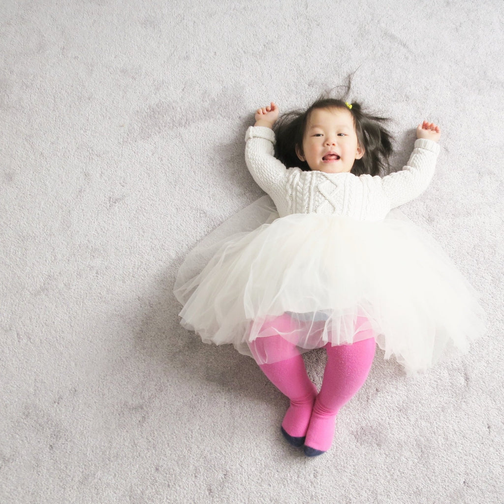 Little girl laying on floor in cream celine tutu by Bluish