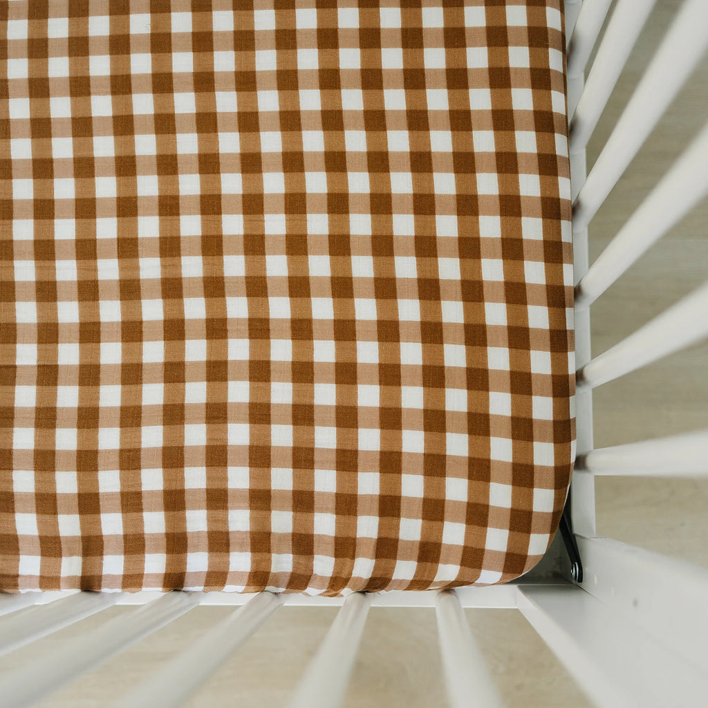 Overhead view of a mattress with the Gingham Crib Sheet by Mebie Baby on it. Crib sheet is a white and brown gingham pattern.