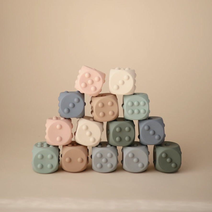Dice Press Toy 2-Pack by Mushie multiple colours stacked on top of each other, with a beige background. 