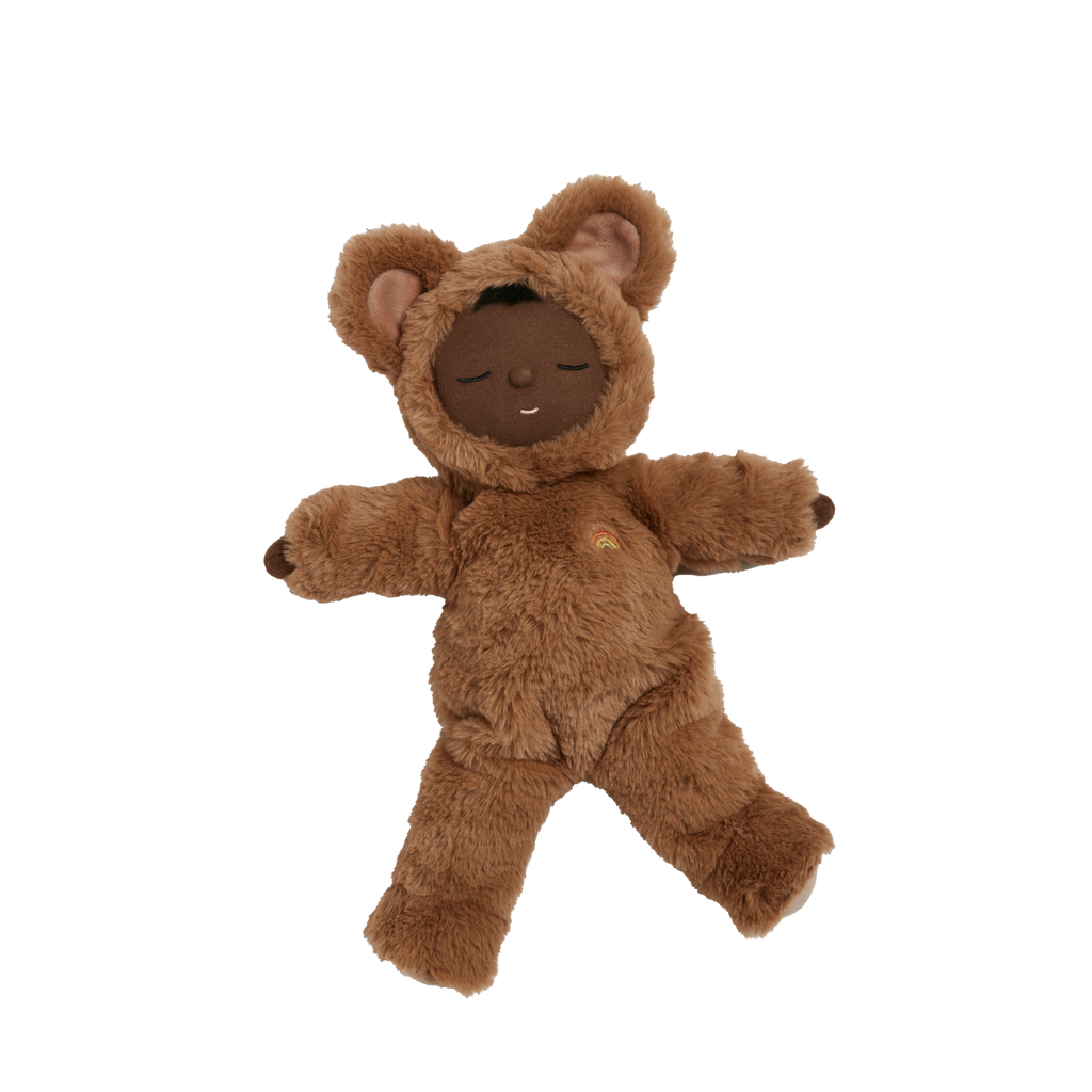 Clear background with Cozy Dinkum Doll Teddy Mini by Olli Ella. Dinkum doll is black, and wearing a fuzzy brown jumpsuit meant to make it look like a teddy bear.