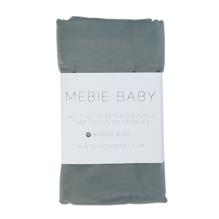 White background with Dusty Blue Stretch Swaddle by Mebie Baby. This shows it folded in the packaging.