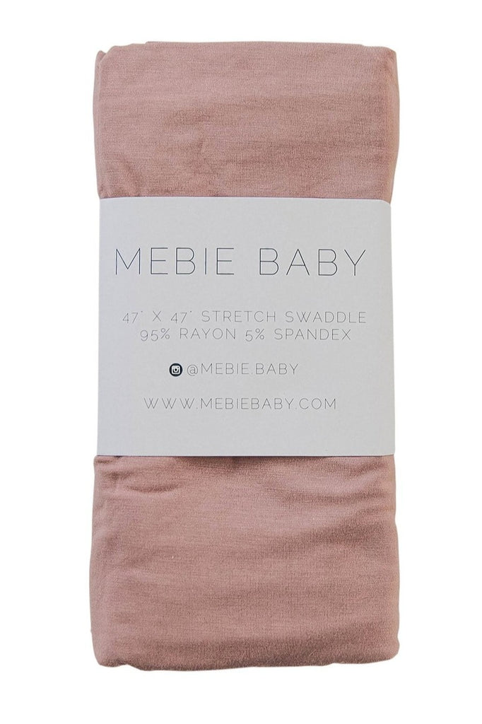 White background with a Dusty Rose Stretch Swaddle by Mebie Baby folded in it's package. 