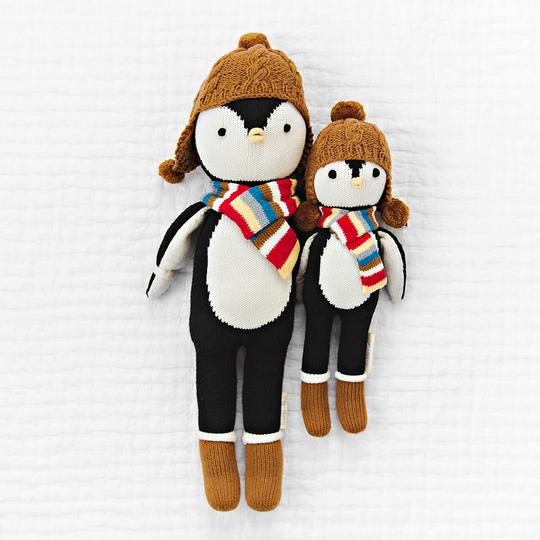 White quilted background with Everest The Penguin by Cuddle and Kind, both sizes laying side by side.