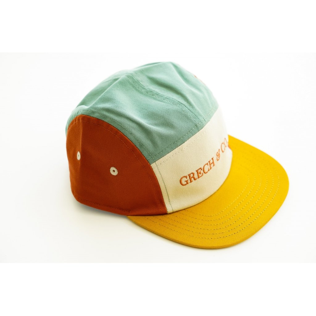 White background with 5 Panel Hat in Fern + Buff by Grech & Co. This hat is a few different colours, greeny/blue, rust, and yellow with a cream front panel with "Grech & Co." in rust across the front.