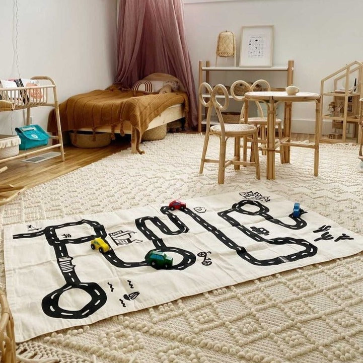 View of a kids bedroom, with the Floor Mat by Imani Collective. Floor mat is linen with a black road drawn on, to look like a city.