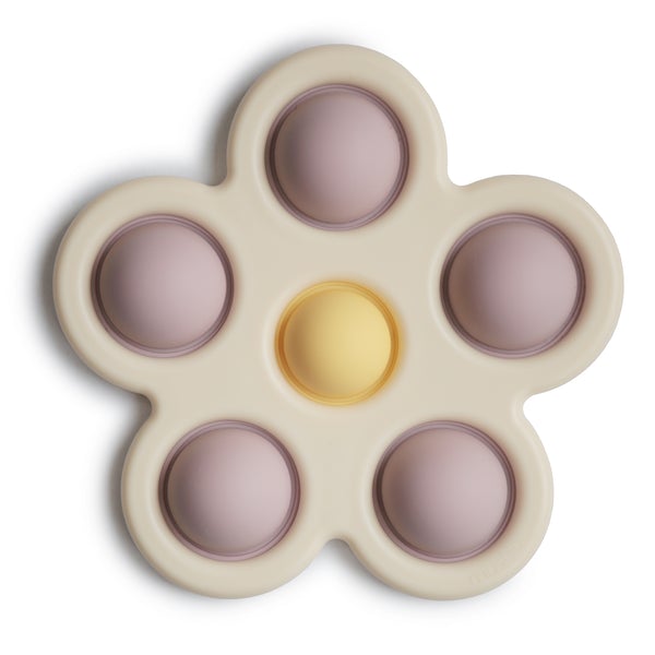 White background with Flower Press Toy in Lilac/Daffodil/Ivory by Mushie. This is a creamy, colour silicone shaped like a 5 point flower, with 5 lilac "pop its" around the outside, and 1 yellow in the center.