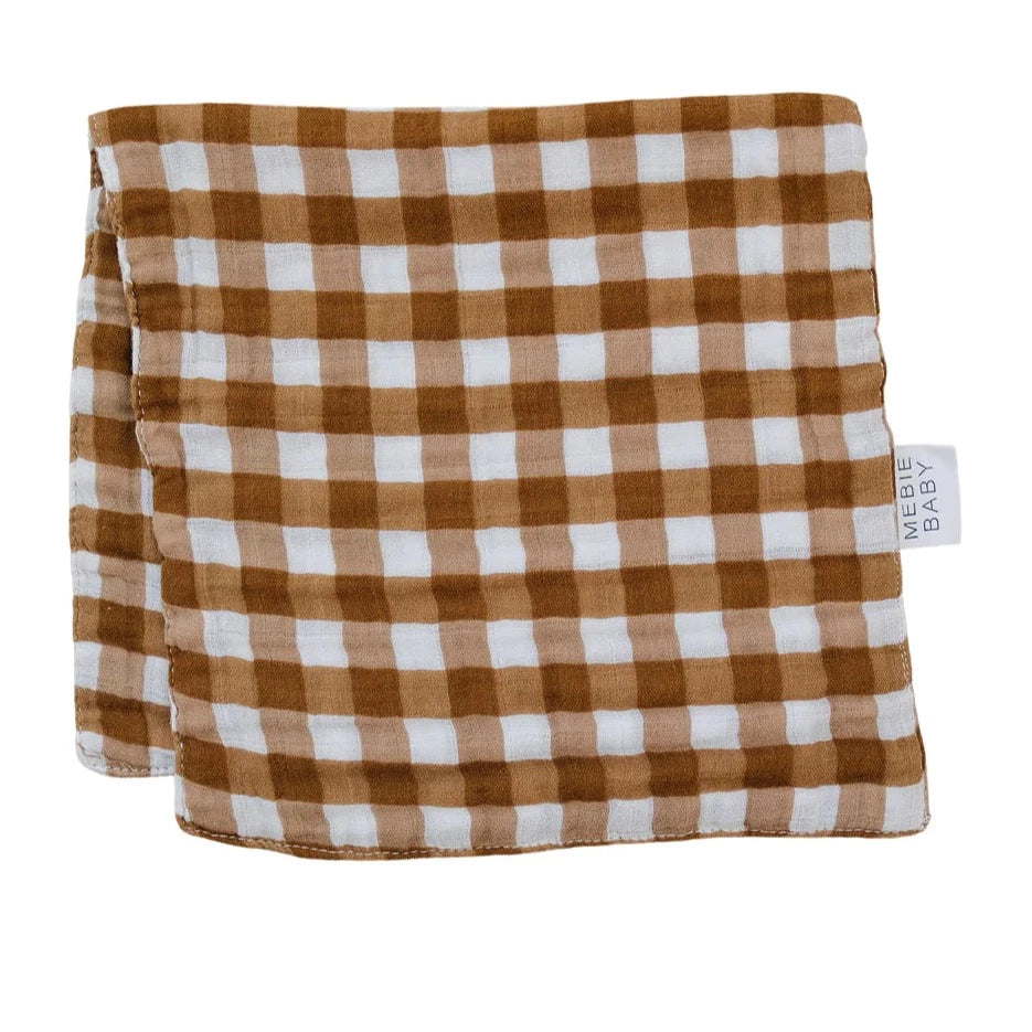 White background with Gingham Burp Cloth by Mebie Baby. Burp cloth is brown and white gingham, with a white tag that says "Mebie Baby".