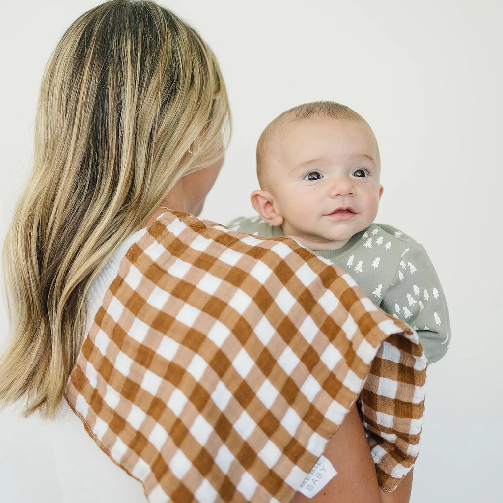 White background with a woman facing away from camera, baby in her arms, and a Gingham Burp Cloth by Mebie Baby over her shoulder.
