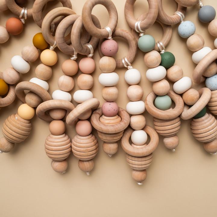 Beige background with a pile of Hand Rattles by Minika.