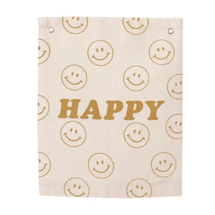 Happy Banner by Imani Collective. Banner has word Happy in gold, with gold smiley faces all over. With 1/2" grommets near the top to hang. White background. 