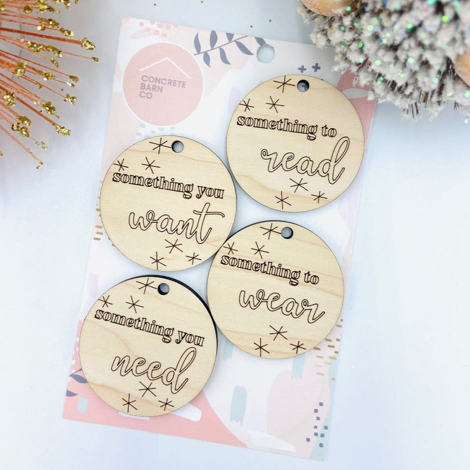 White background with an overhead view of the Holiday Gift Tags by Concrete Barn in their packaging. There are 4 tags, they are round and engraved wood.