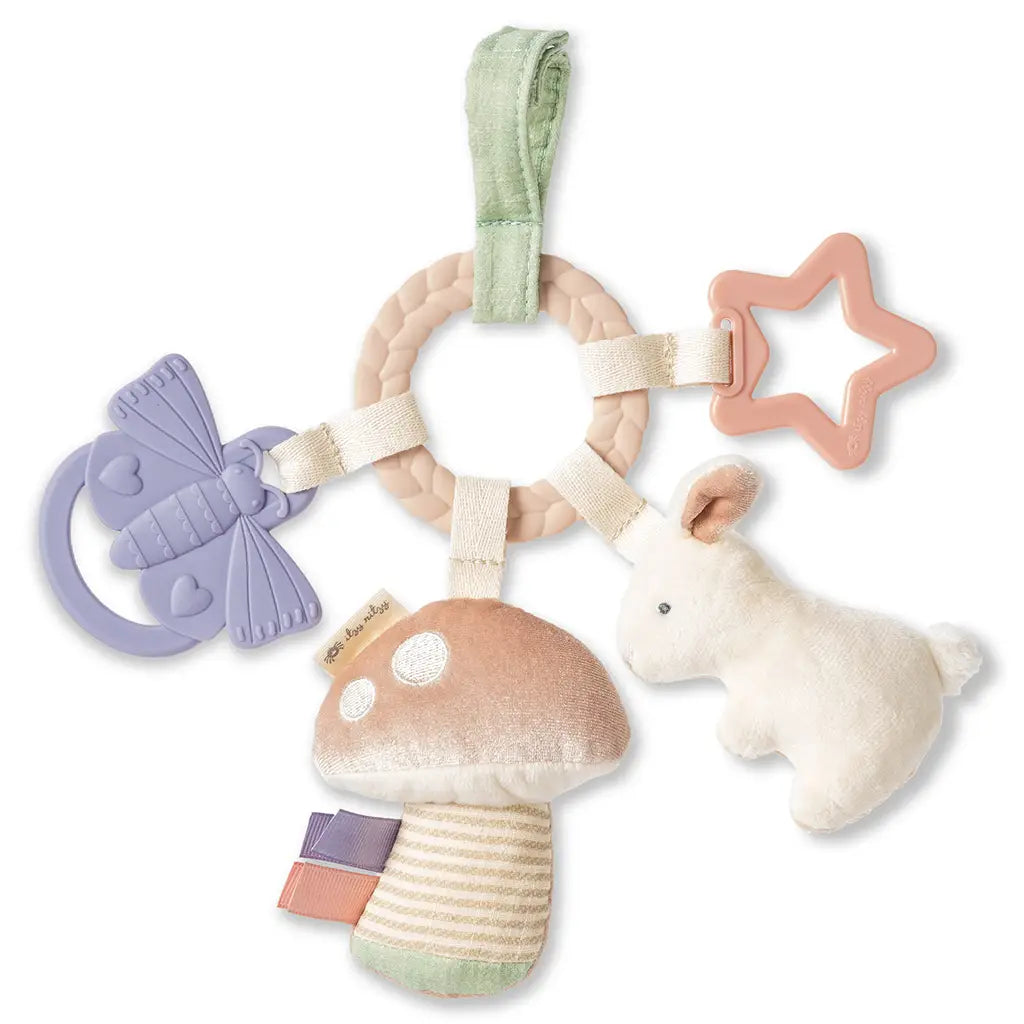 White background with Bitzy Busy Ring Teething Activity Toy Bunny by Itzy Ritzy. This is a ring teether that can attach to your stroller, and has 4 toys. A Star, a butterfly, a plush crinkly mushroom, and a bunny rattle.