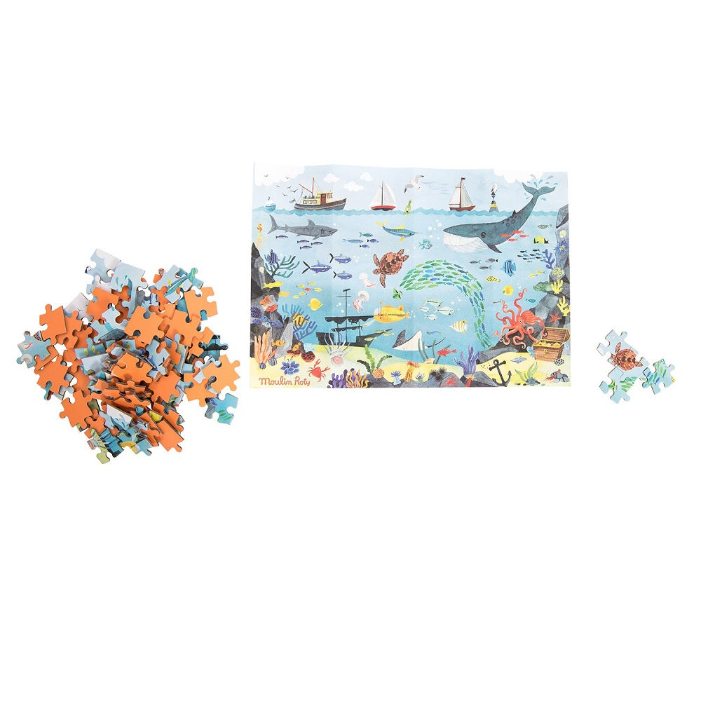 White background with L'Ocean Explorateur Puzzle by Moulin Roty, all put together, and puzzle pieces. This puzzle is of an ocean scene.