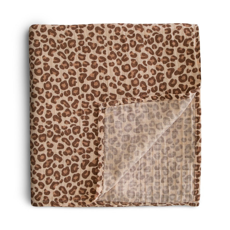Muslin Swaddle Blanket Organic Cotton in Leopard by Mushie folded on a white surface. 