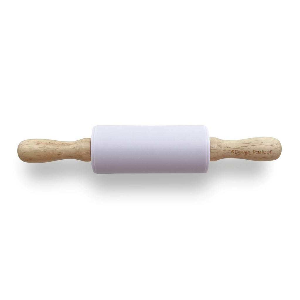 White background with the Silicone Roller in Lilac by Dough Parlour. Roller has wood handles, and a silicone rolling pin in a lilac colour.