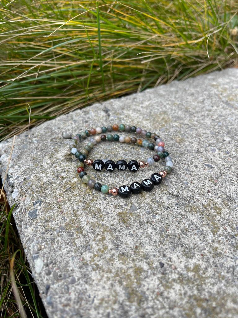 Indian Agate Mama Bracelets by Earth & Ether Co., laid on concrete in front of green grass. 