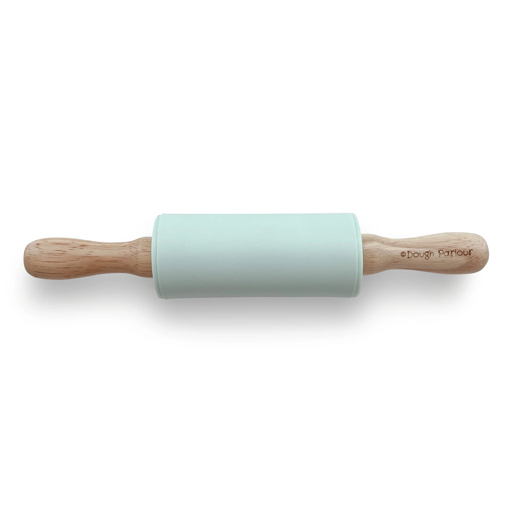 White background with the Silicone Roller in Mint by Dough Parlour. Roller has wooden handles and a mint green silicone rolling pin.
