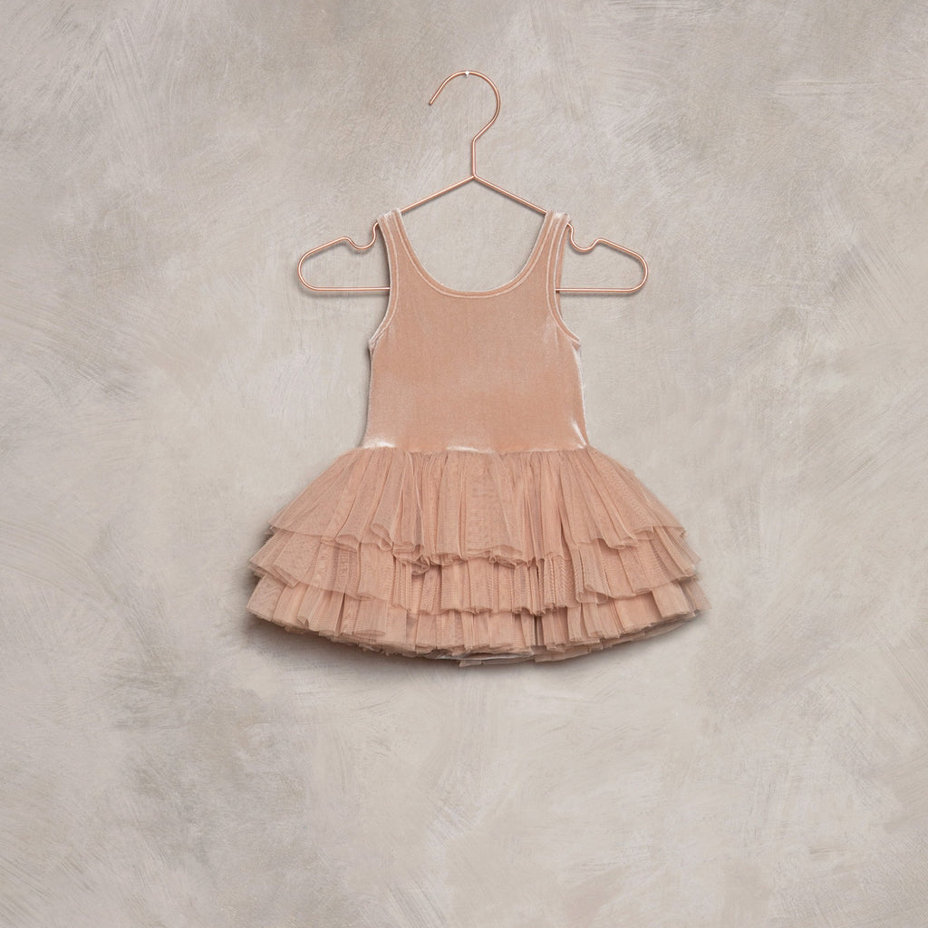 Tallulah Tutu in Dusty Rose by Noralee hung on a rose gold hanger, laid against a grey wall. 