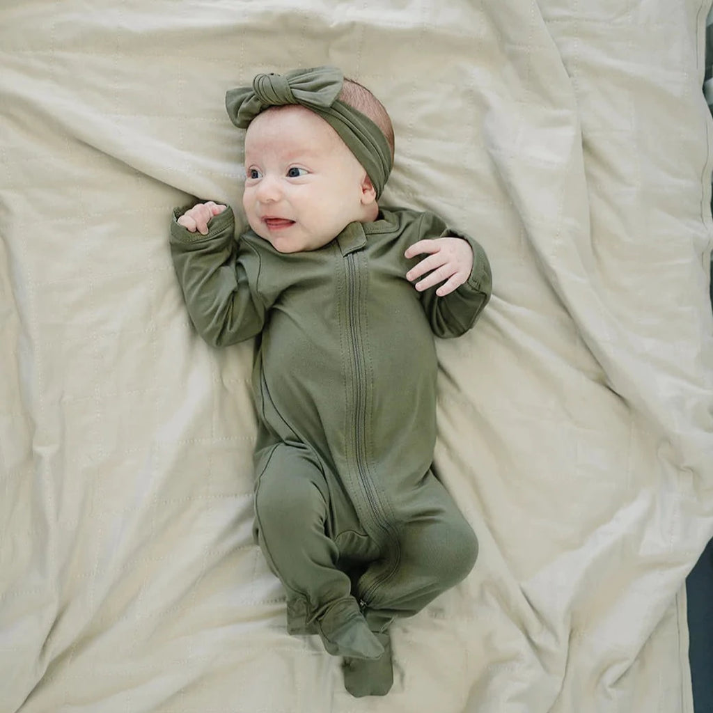 Overhead view of a baby laying on the Oatmeal Bamboo Quilt by Mebie Baby.