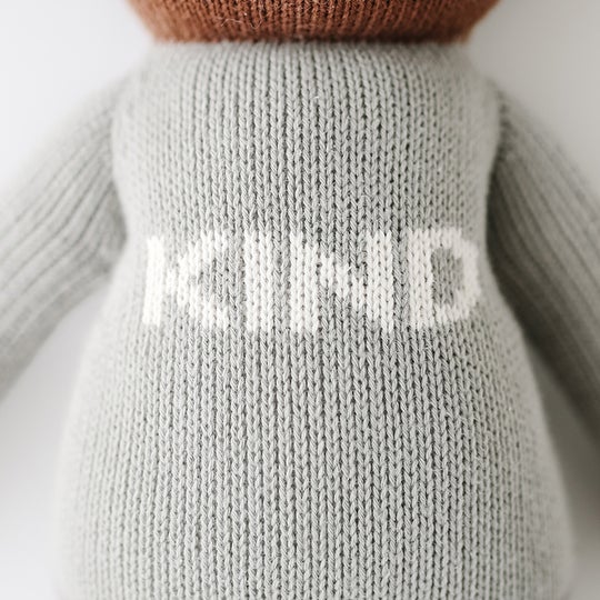 Close up of knitted top, says "KIND" on Oliver The Bear by Cuddle and Kind