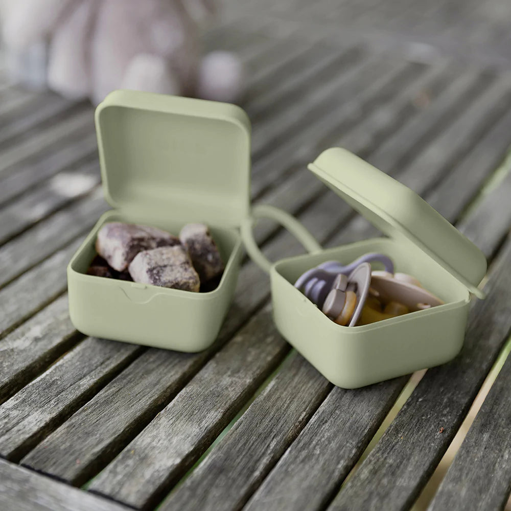 Overhead view of 2 Pacifier Boxes in Sage by Bibs on a deck.